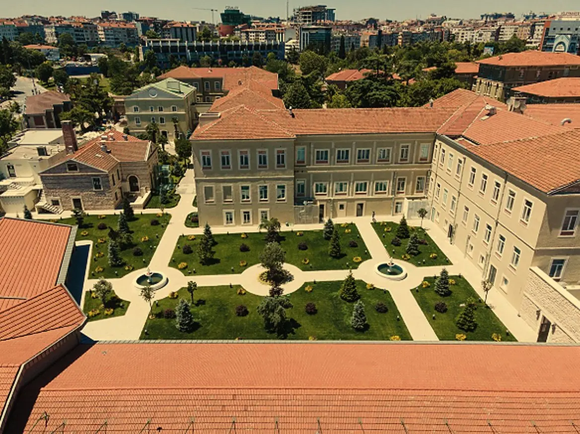 The hospital from above: historic buildings with red tiled roofs around a garden courtyard